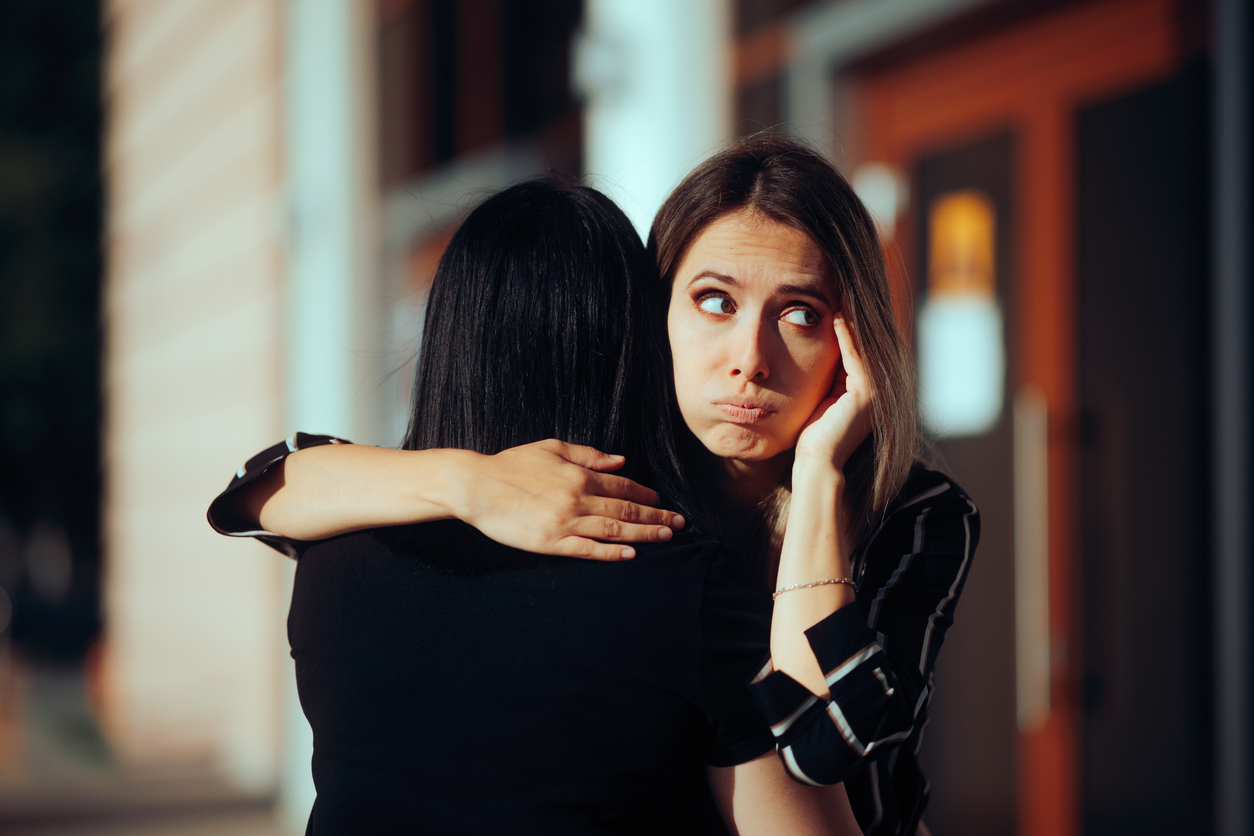 woman holding her breath while hugging a stinky friend