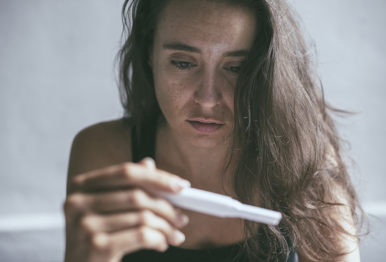 woman looking at a negative prenancy test
