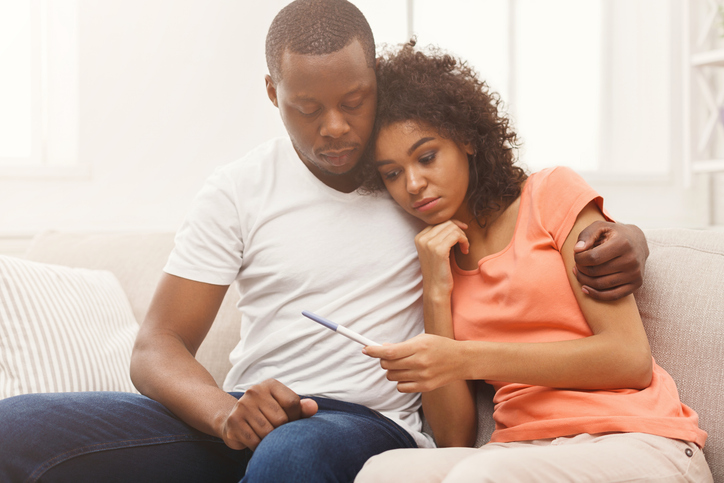 disappointed couple looking at a negative pregnancy test