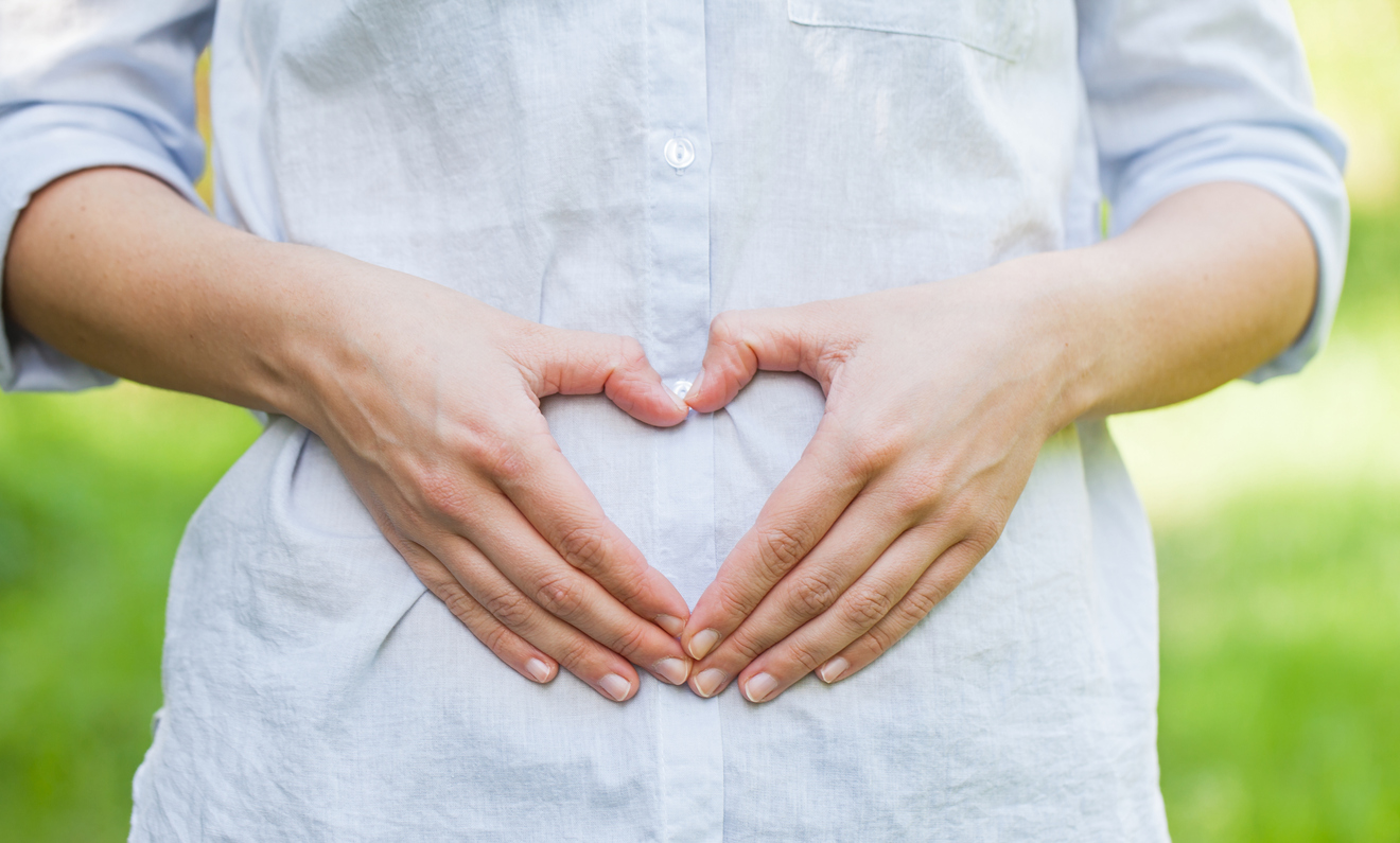 pregnant woman making a heart with her hands on her baby bump