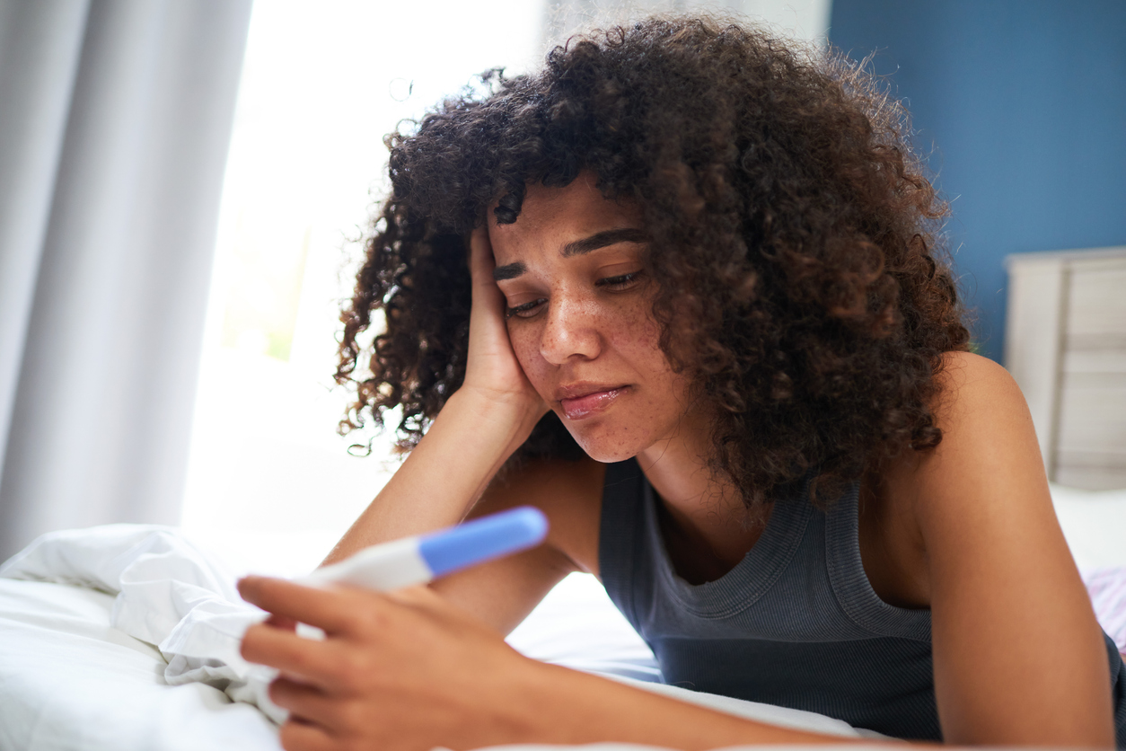 sad woman looking at a negative pregnancy test