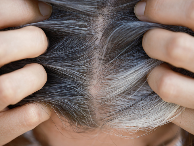 woman with grey hairs pulling at her part