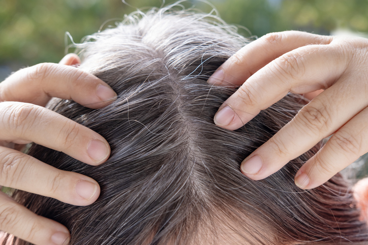 woman with gray hairs massaging her scalp