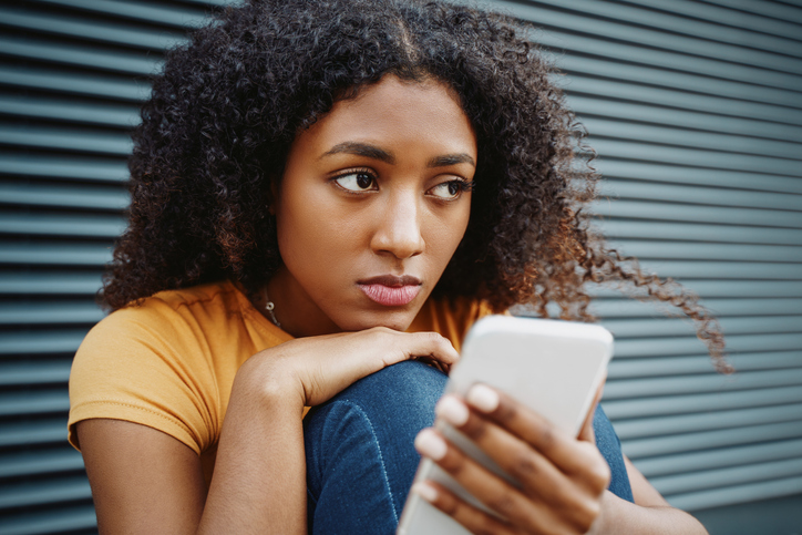 woman struggling with mental health issues looking up from her phone