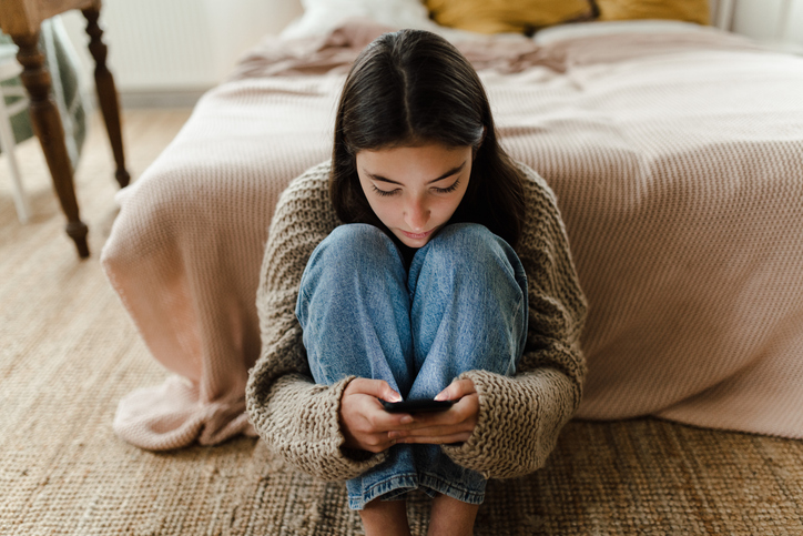 young woman isolated in her room looking at her socials