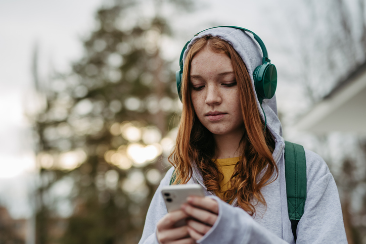 young woman with headphones on looking at her phone