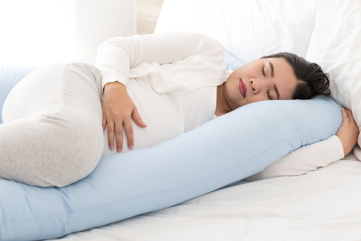 pregnant woman sleeping soundly with a u-shaped pregnancy pillow