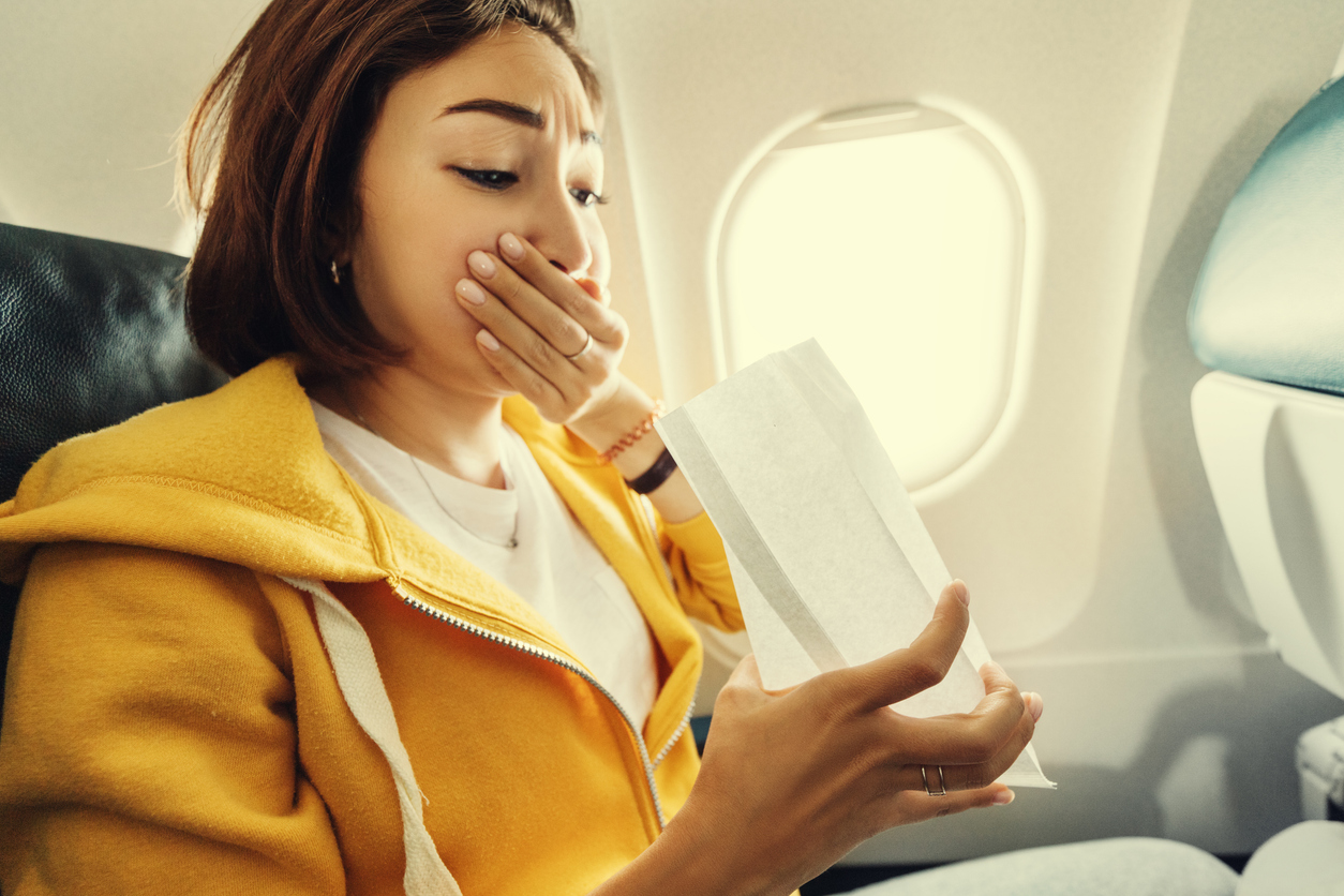 woman using an airsick bag on the plane