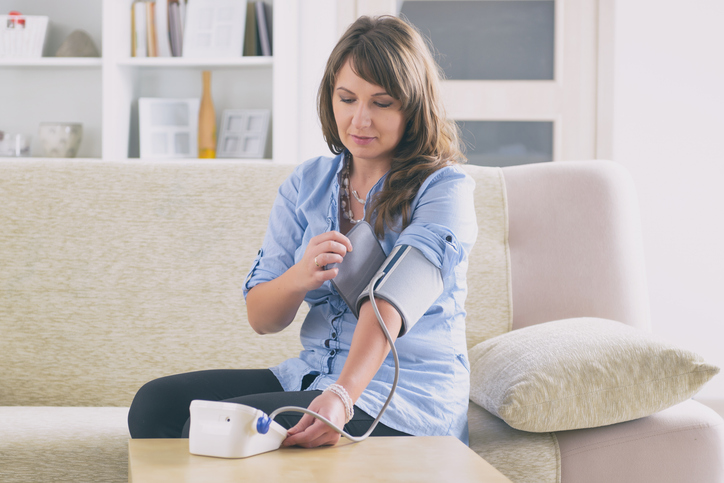 woman checking her blood pressure after pregnancy