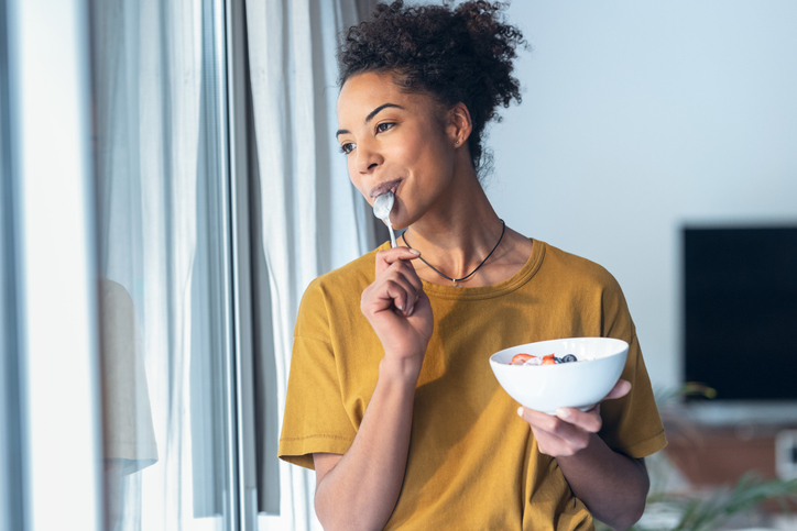 woman eating full fat yogurt and fruits high in coq10
