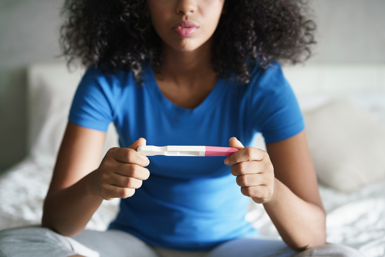 woman staring at an at-home pregnancy test