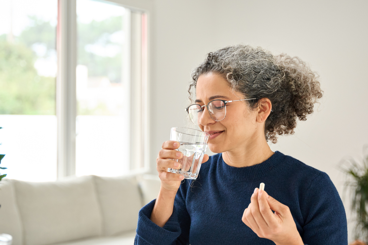 woman taking a postnatal vitamin with water