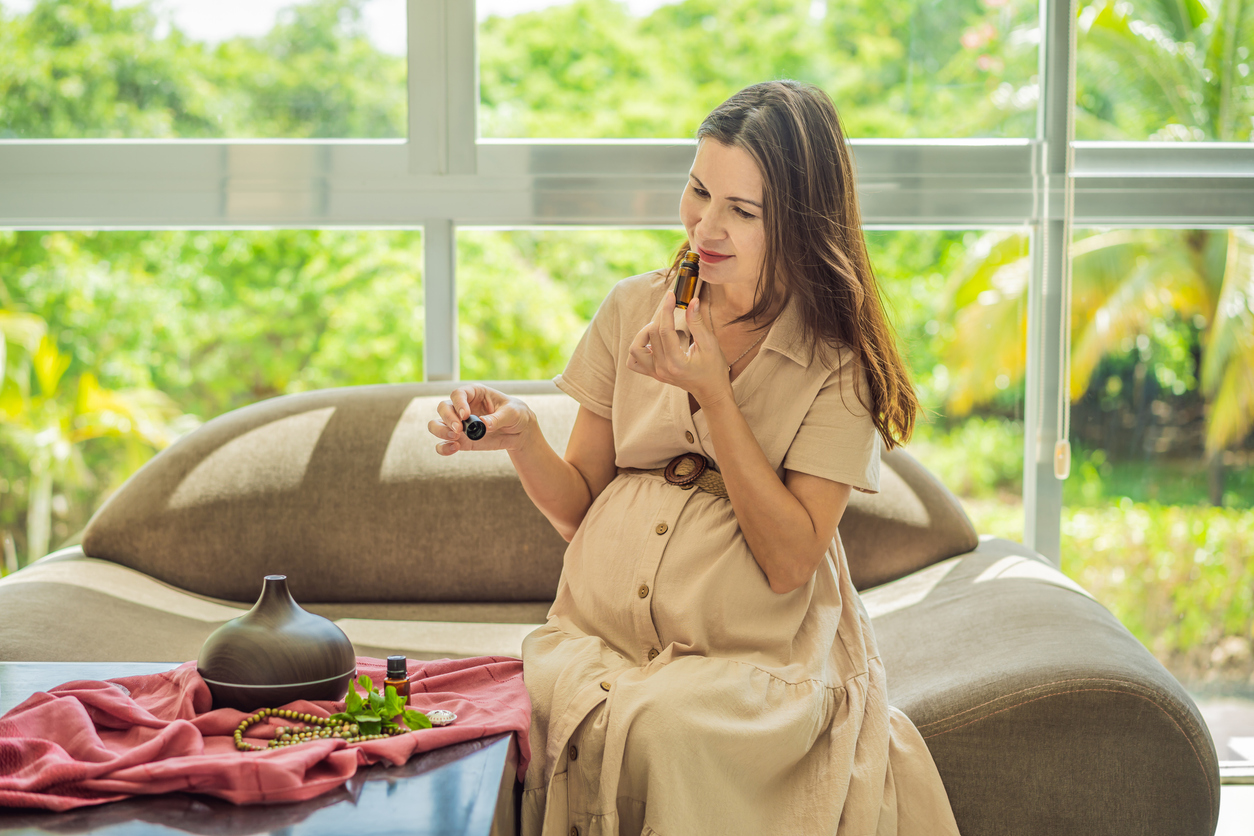 pregnant woman putting essential oil in a diffuser