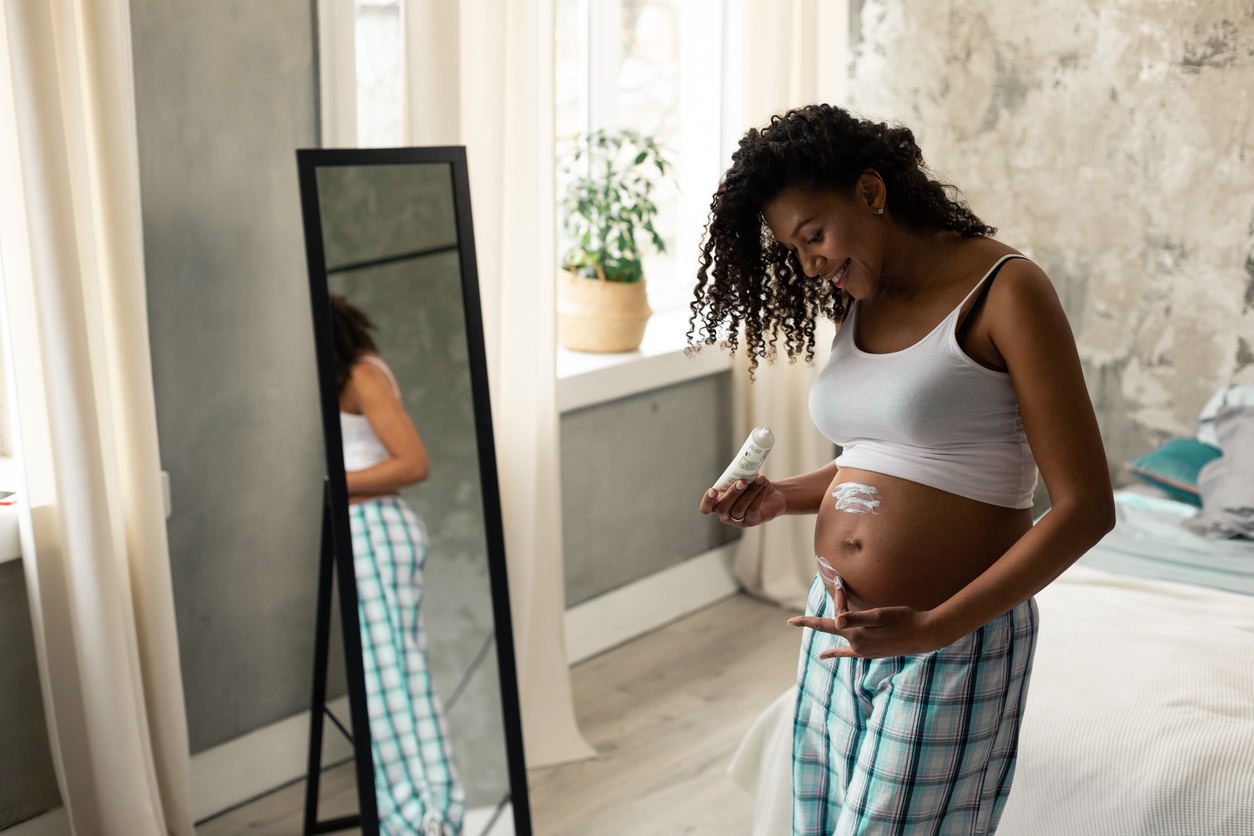woman putting cream on her pregnant belly