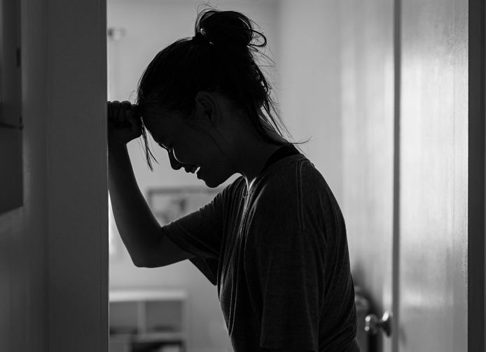 woman with postpartum rage crying and beating the wall