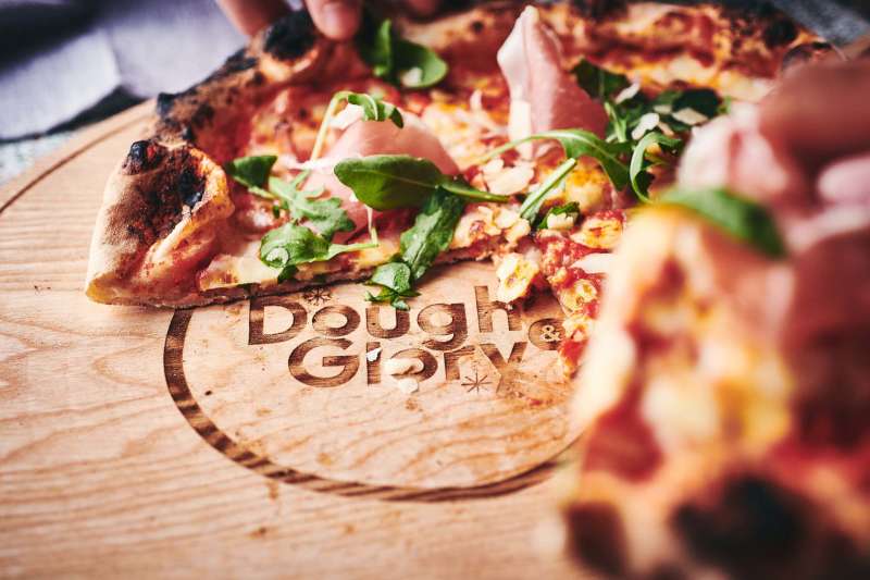 Friends enjoying a slice of Dough and Glory pizza