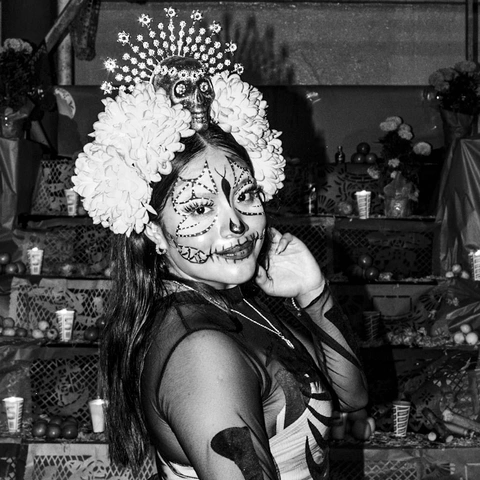 Женщина с черепным макияжем, венком из цветов и маленьким черепом перед алтарем