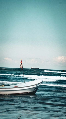 Barco branco com bandeira tremulando em água do mar com ondas suaves