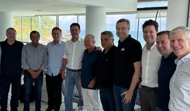 Reunião estratégica do PSD-SC em Florianópolis reúne lideranças políticas para discutir eleições de 2026. Na imagem, o governador Ratinho Júnior (PR) ao centro, ladeado por figuras importantes como Raimundo Colombo, Júlio Garcia, Topázio Neto, Jorge Bornhausen, João Rodrigues, Napoleão Bernardes, Guto Silva, Eron Giordani e Eduardo Sciarra, durante encontro que traçou os rumos do partido para os próximos pleitos eleitorais.