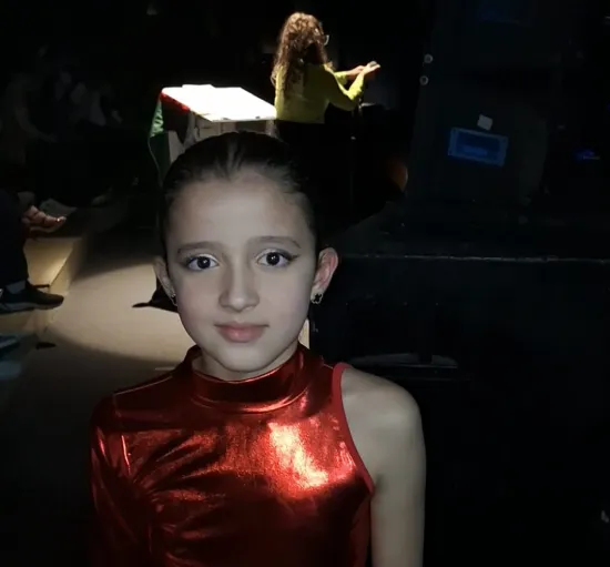 Crianças do Colégio Bliss (São José) se apresentam na 17ª Mesorregional do Festival Escolar Dança Catarina, na coreografia “Um vestido para ela”, da categoria Mirim Livre – Temática 1. As bailarinas usam figurino com orelhinhas de rato e saias lilás, dançando em frente a um manequim com vestido de gala, em destaque no palco.
