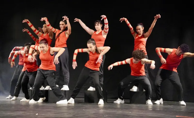 Crianças do Colégio Bliss (São José) se apresentam na 17ª Mesorregional do Festival Escolar Dança Catarina, na coreografia “Um vestido para ela”, da categoria Mirim Livre – Temática 1. As bailarinas usam figurino com orelhinhas de rato e saias lilás, dançando em frente a um manequim com vestido de gala, em destaque no palco.