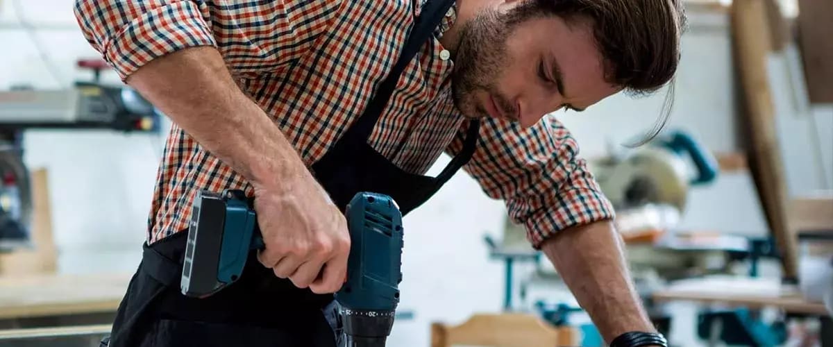 Tischler in der Werkstatt mit einem Bohrer in der Hand.