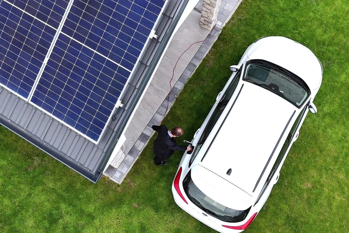 Luftaufnahme E-Auto an Wallbox neben Haus mit PV