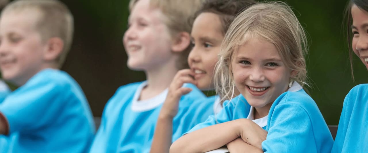 Eine Gruppe von lächelnden Kindern in blauen Trikots.