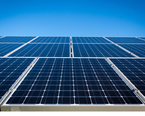 Reihe von dunkelblauen Solarmodulen unter klarem, blauem Himmel – Symbol für nachhaltige Energieerzeugung durch Photovoltaik.