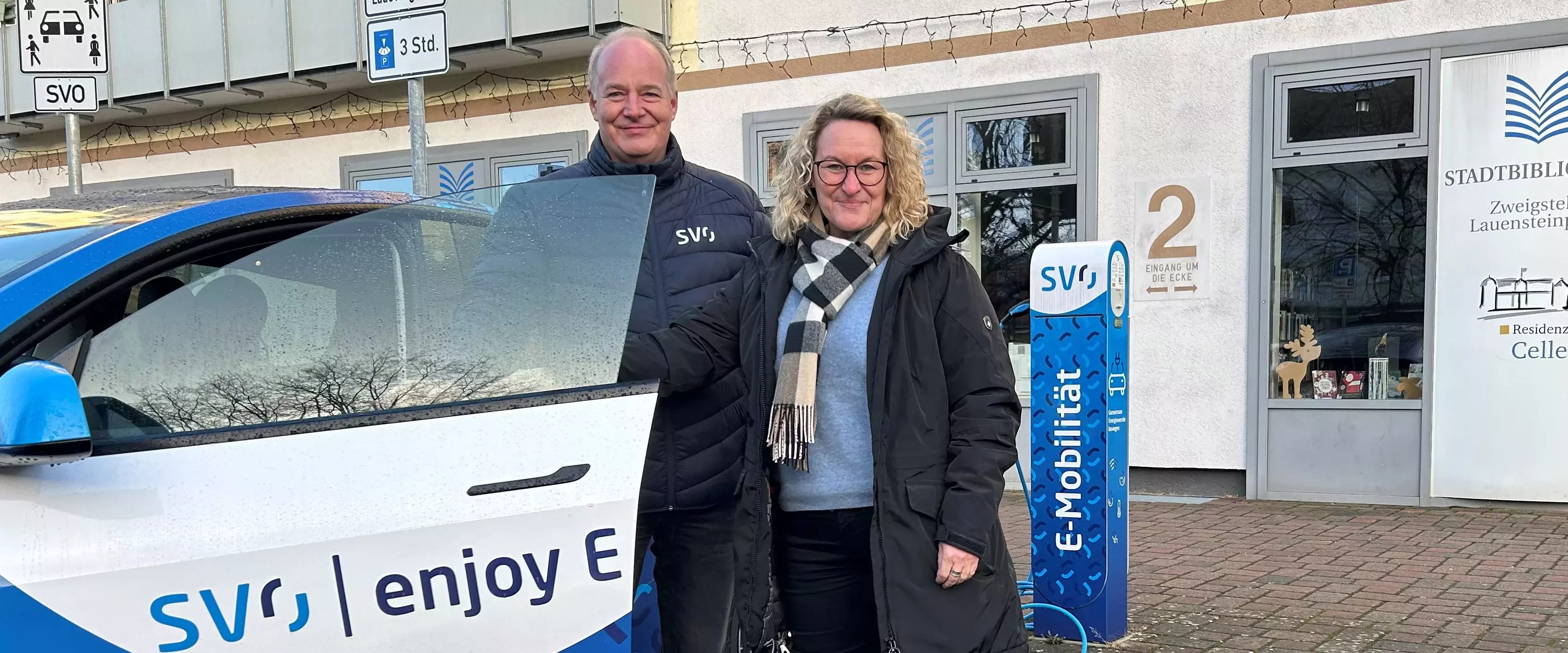 Zwei Personen vor E-Ladesäule und Elektroauto der SVO, vor Stadtbibliothek Celle.