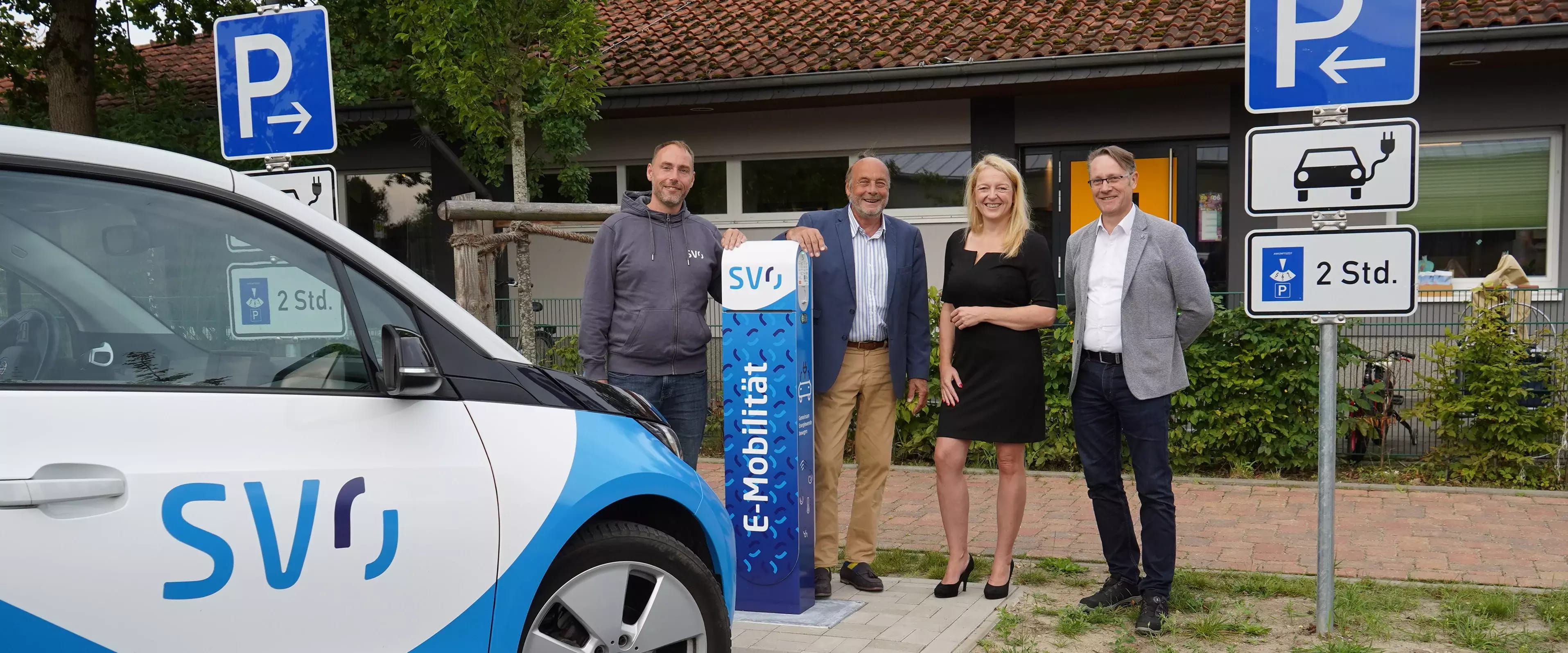 Vier Personen neben E-Ladesäule der SVO, im Vordergrund Elektroauto.