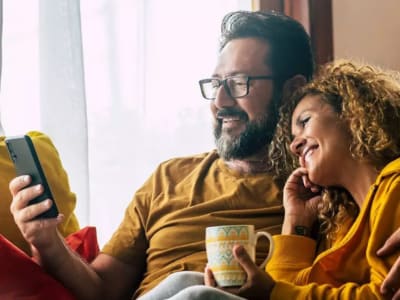 Paar schaut lächelnd auf Smartphone.