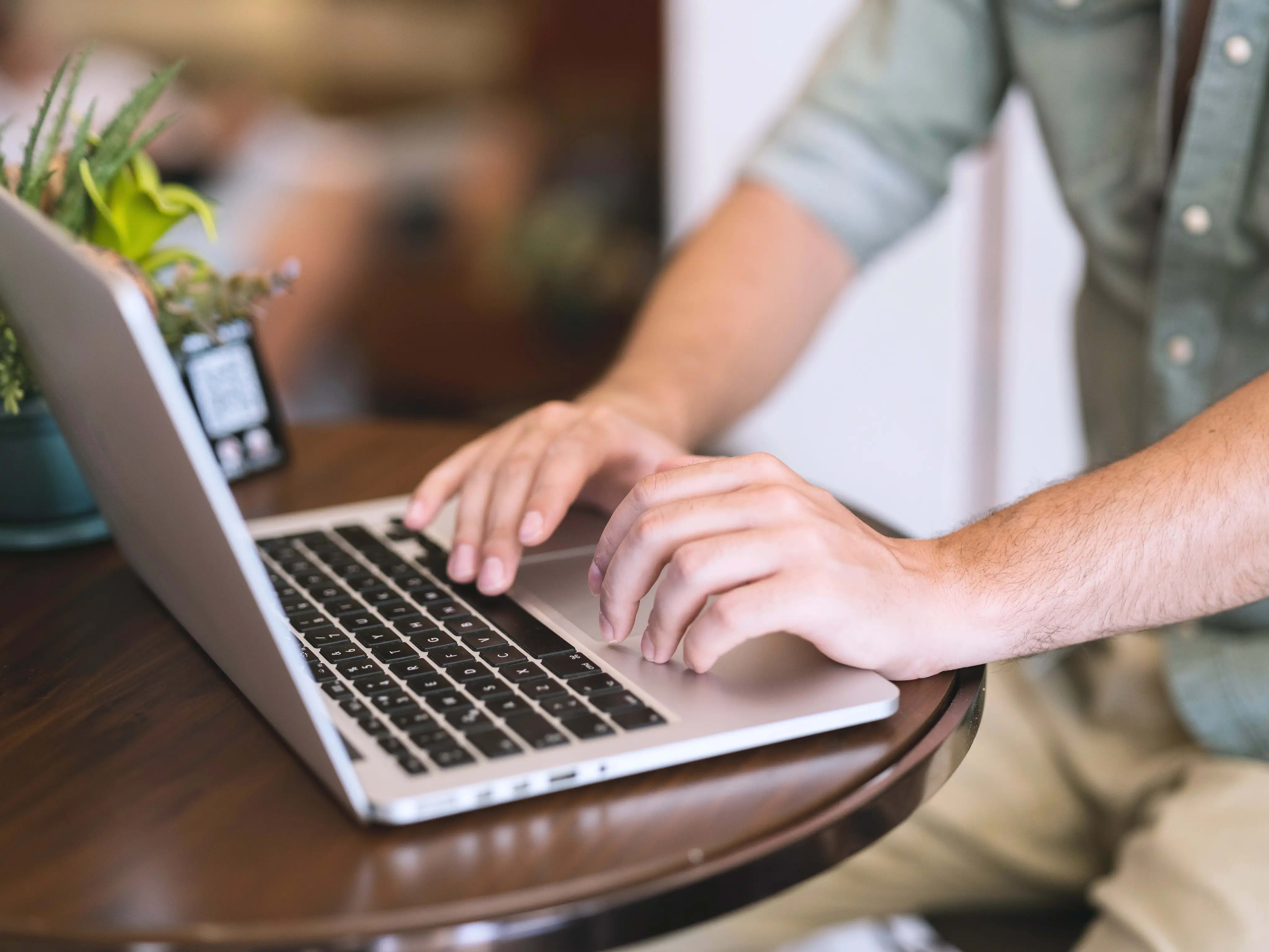 Männliche Hände tippen am Laptop.