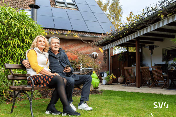 Familie Voß sitzen gemeinsam auf einer Bank in ihrem Garten.