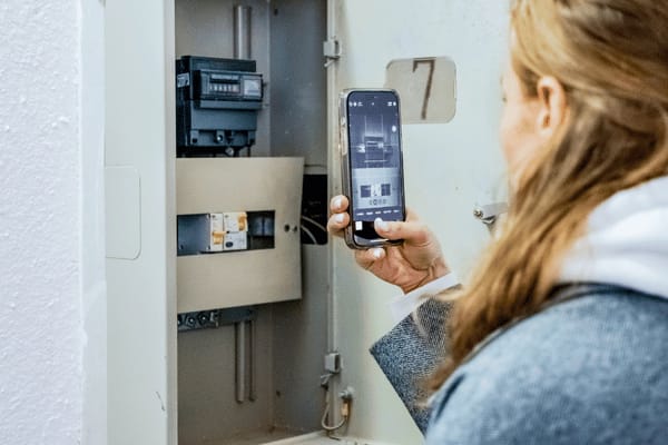 Junge Frau liest den Zählerstand per Foto ab.