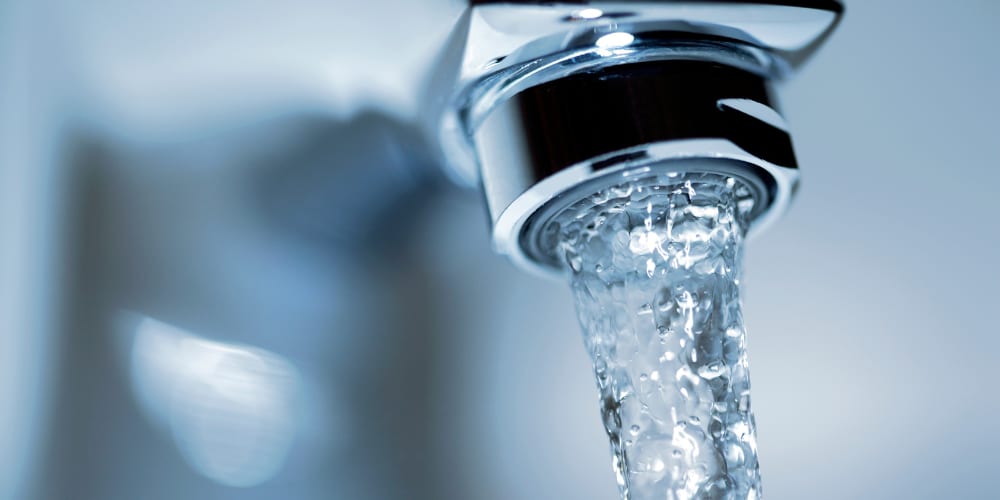 Ein geöffneter Wasserhahn, aus dem klarer Wasserstrahl fließt.