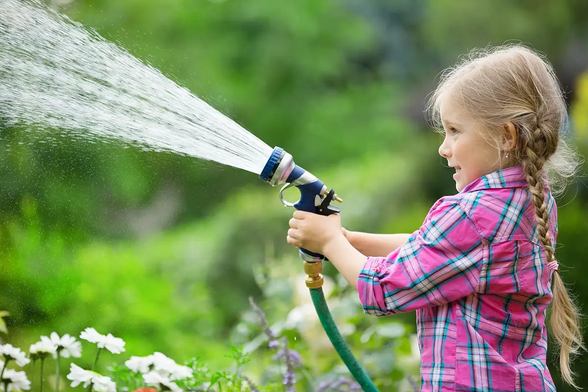 Kind mit Gartenschlauch