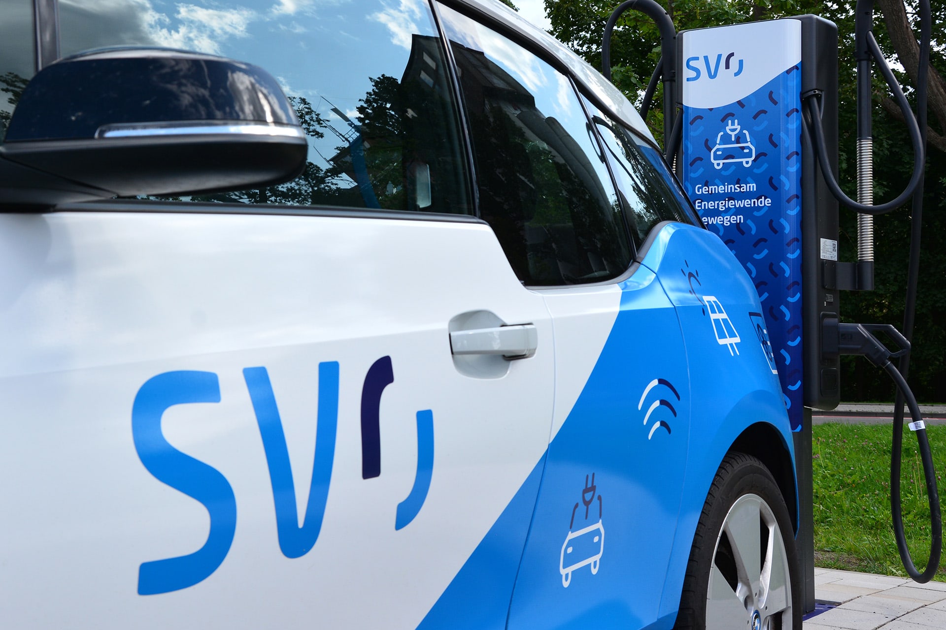 E-Auto mit SVO Logo parkt vor einer Ladesäule.