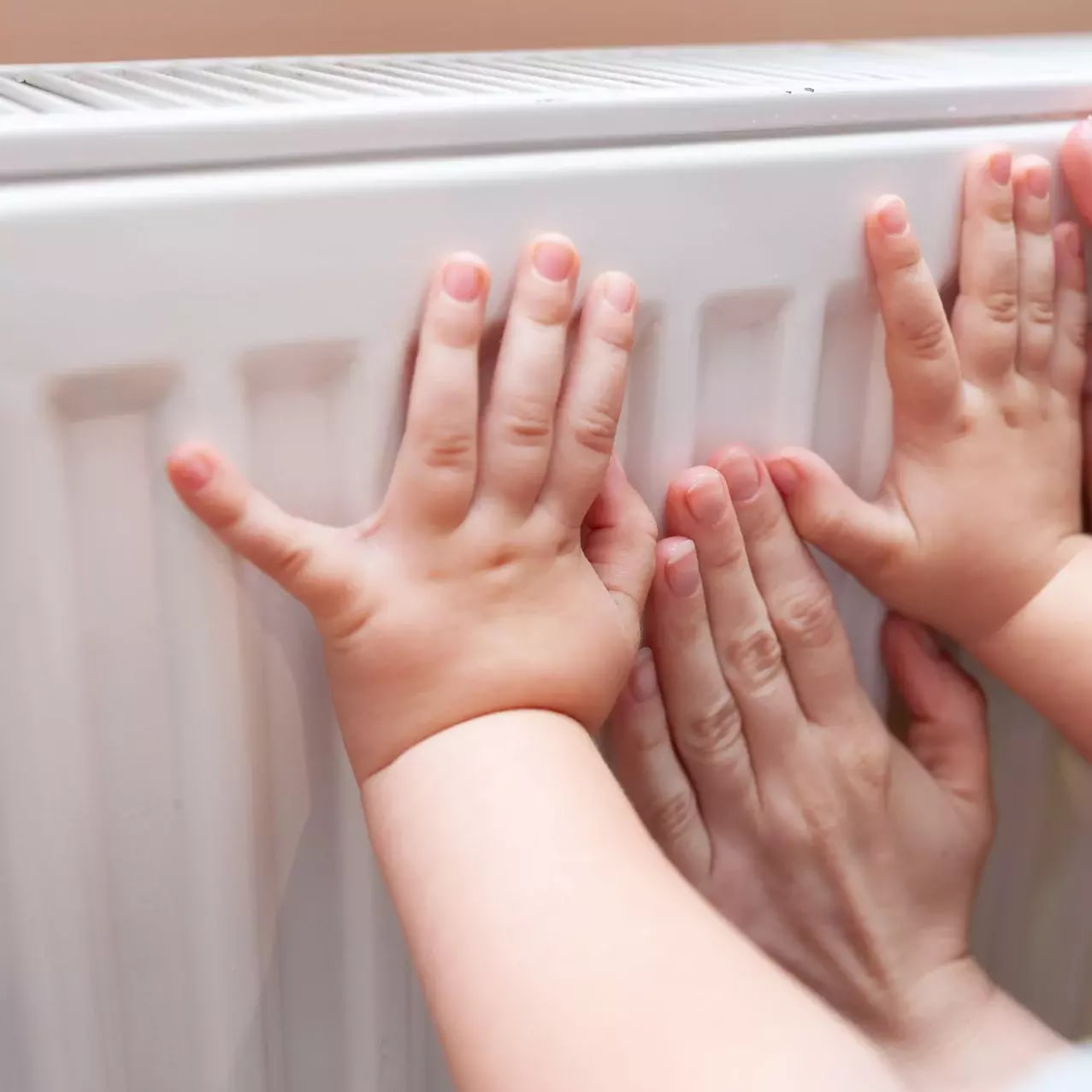 Hände werden an Heizkörper gewärmt, der durch Erdgas erwärmt wird