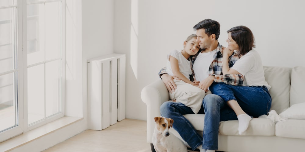 Eine Familie mit Kind kuschelt auf einem weißen Sofa.