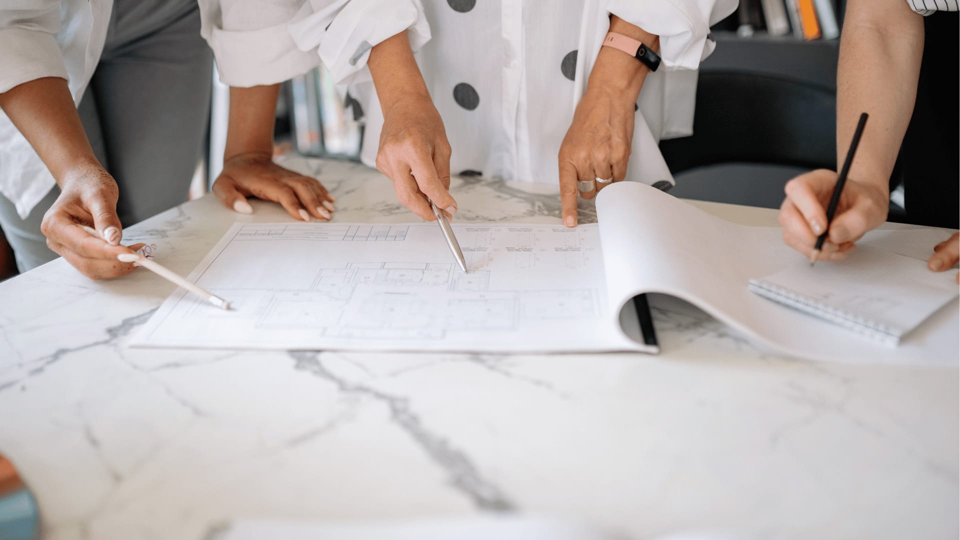 Mehrere Personen besprechen gemeinsam eine Elektroplanung anhand eines Bauplans auf einem Tisch.