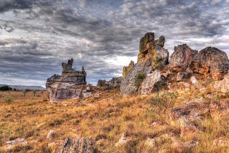 Weathered rock formations rising from dry grassland under a cloudy sky in Madagascar