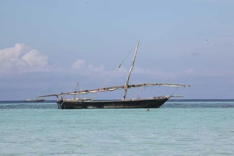 Traditional dhow boat anchored in calm turquoise water off Zanzibar's coast
