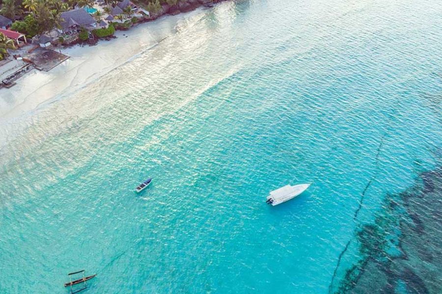 Aerial view of a beachfront resort in Zanzibar with boats anchored in turquoise water