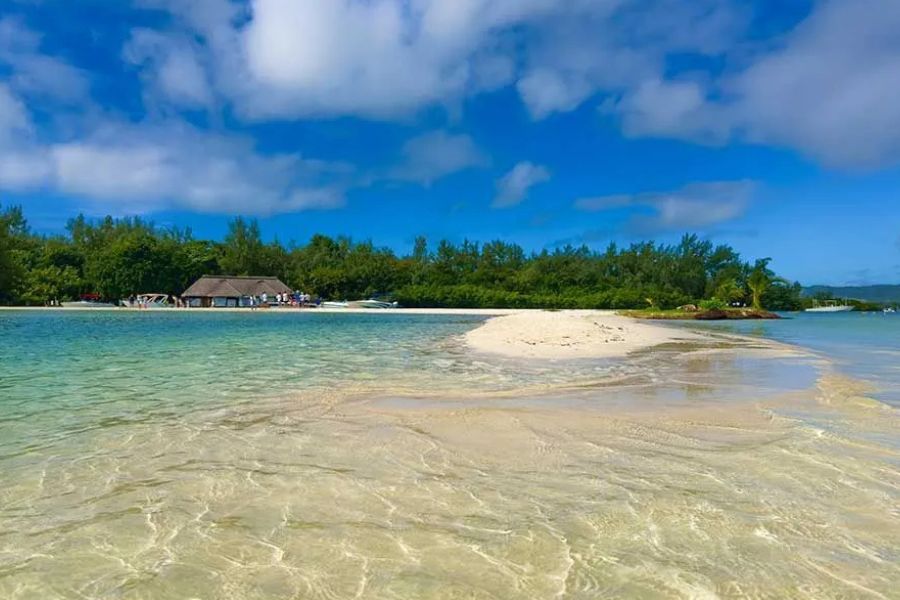 Sandbank in a turquoise lagoon with a thatched hut and boats nearby in Mauritius