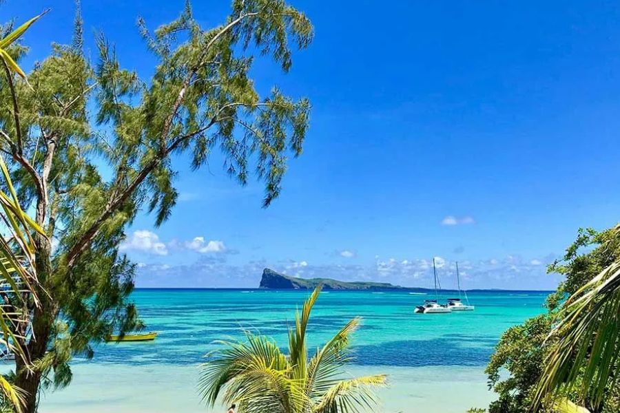 Turquoise lagoon with catamarans anchored, an island visible in the distance