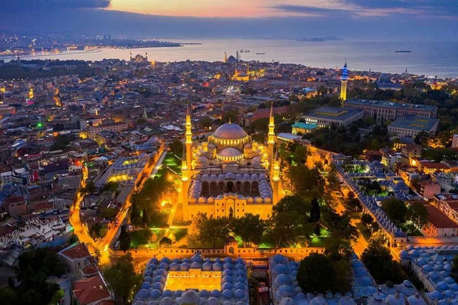 Aerial night view of a grand illuminated mosque overlooking Istanbul's waterfront