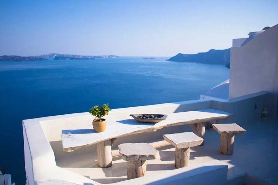 Wooden terrace overlooking Santorini's caldera and the sea, white buildings nearby