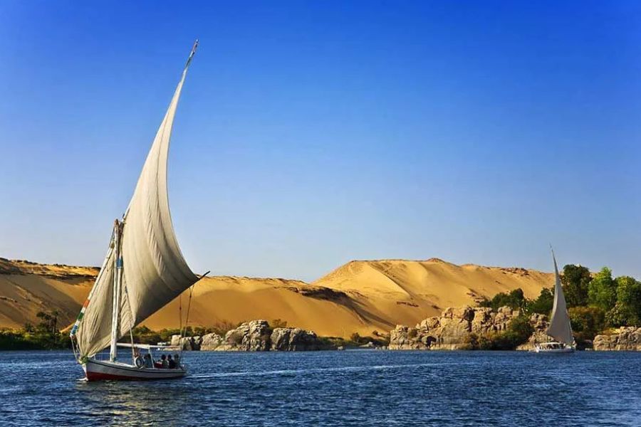 Traditional felucca sailboat on the Nile River, sand dunes in the background