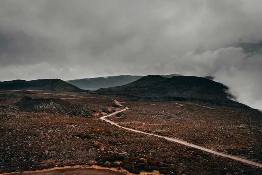 Winding dirt road through Réunion's volcanic highlands under low clouds